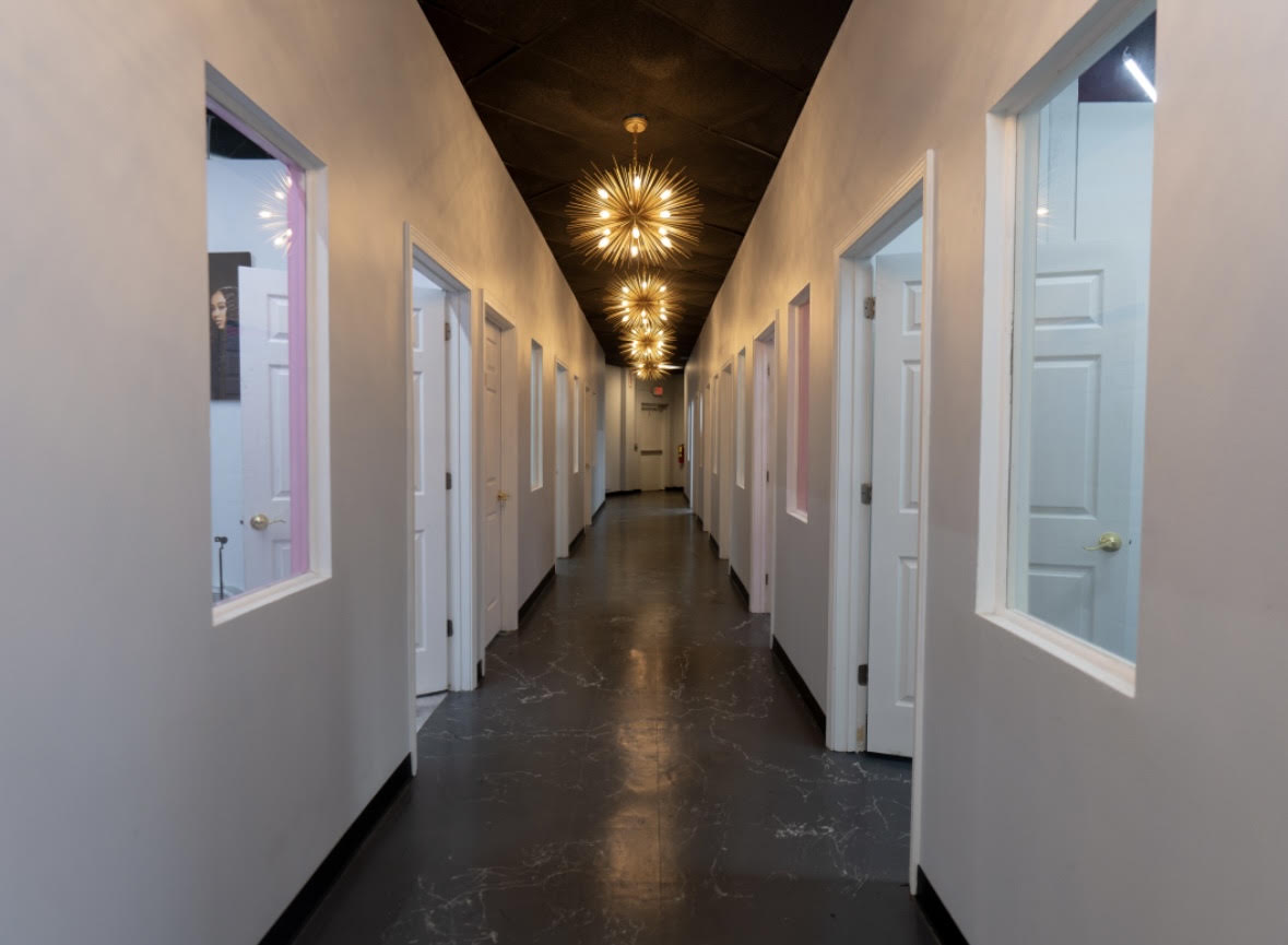 Salon suite hallway with private suite doors and gold starburst chandeliers